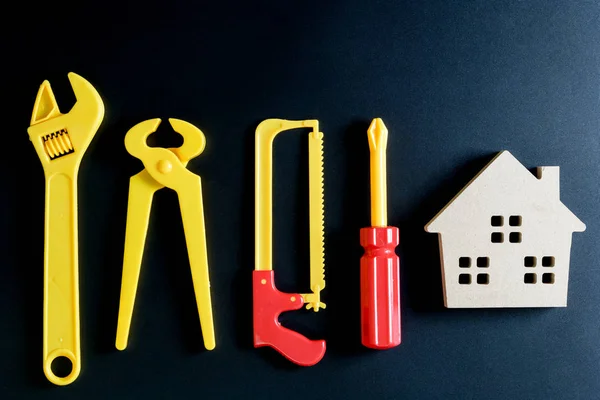 Juguete de casa de madera y juguete de herramientas de construcción sobre fondo negro — Foto de Stock