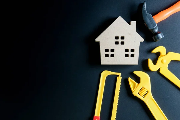 Juguete de casa de madera y juguete de herramientas de construcción sobre fondo negro — Foto de Stock