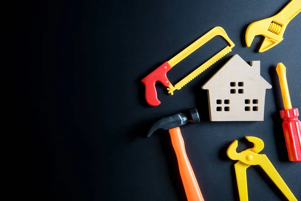 Juguete de casa de madera y juguete de herramientas de construcción sobre fondo negro — Foto de Stock