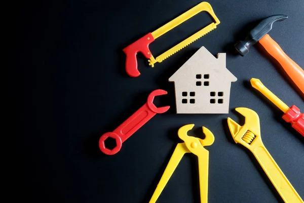 Juguete de casa de madera y juguete de herramientas de construcción sobre fondo negro — Foto de Stock