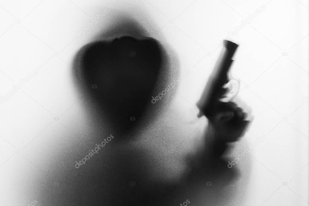 Shadow blur of horror man in jacket with hood gun in his hand.Da