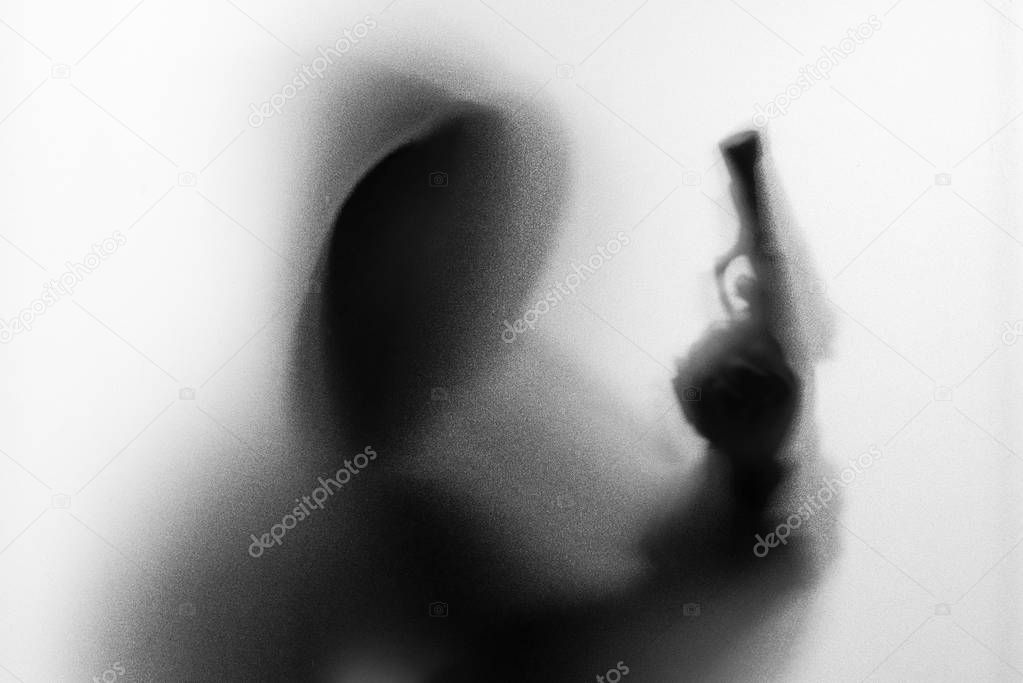Shadow blur of horror man in jacket with hood gun in his hand.Da
