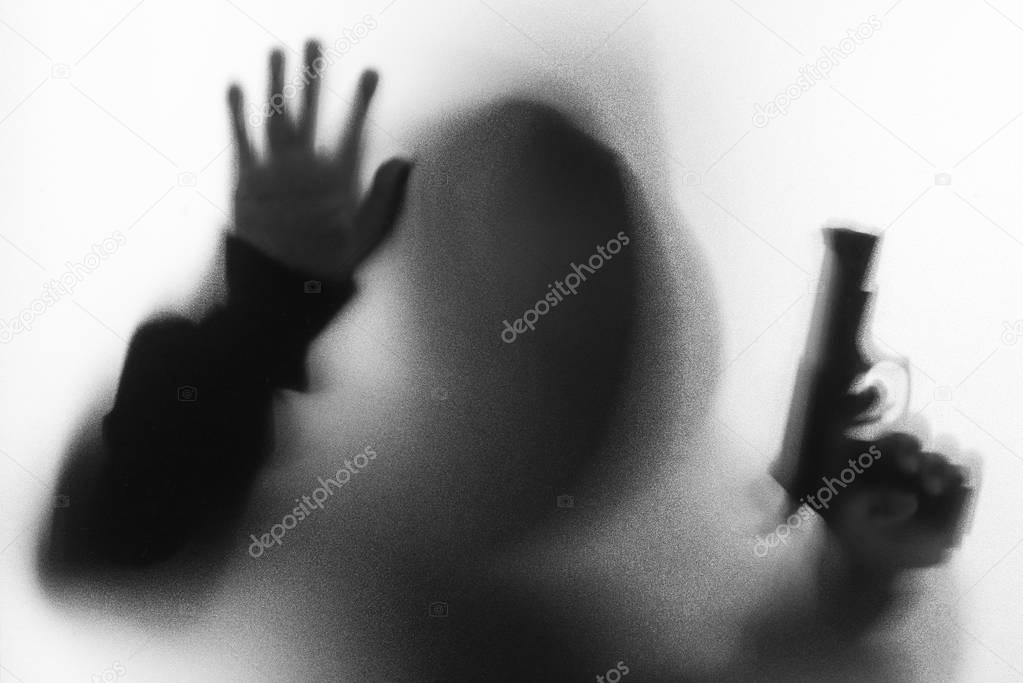 Shadow blur of horror man in jacket with hood gun in his hand.Da