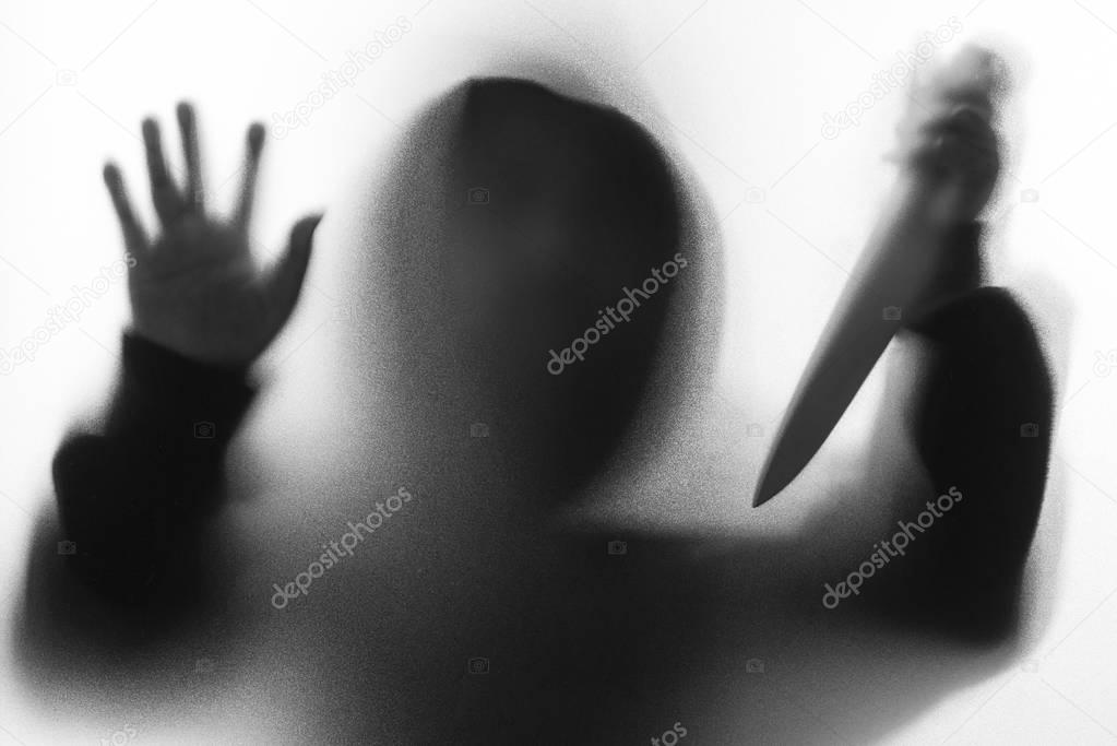 Shadow blur of horror man in jacket with hood knife in his hand.