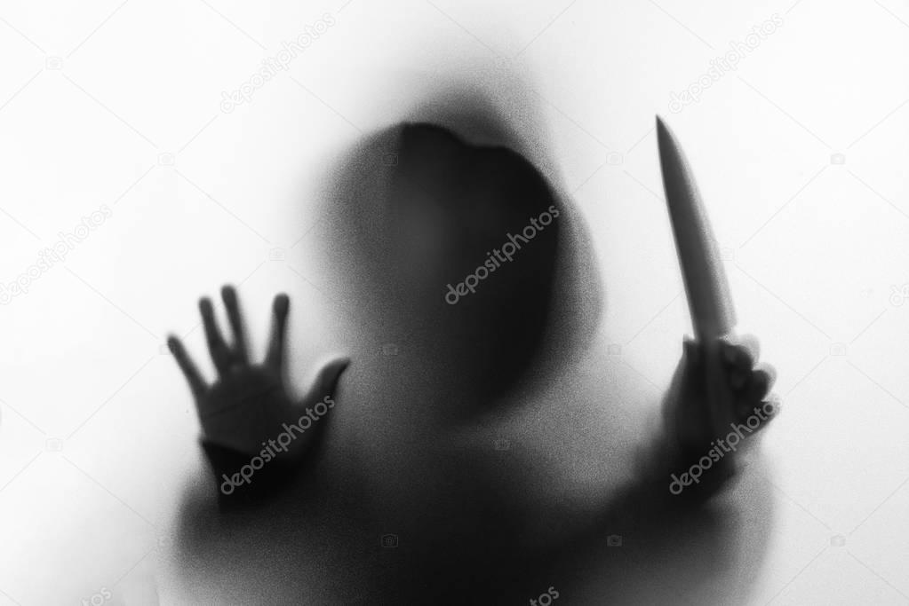 Shadow blur of horror man in jacket with hood knife in his hand.