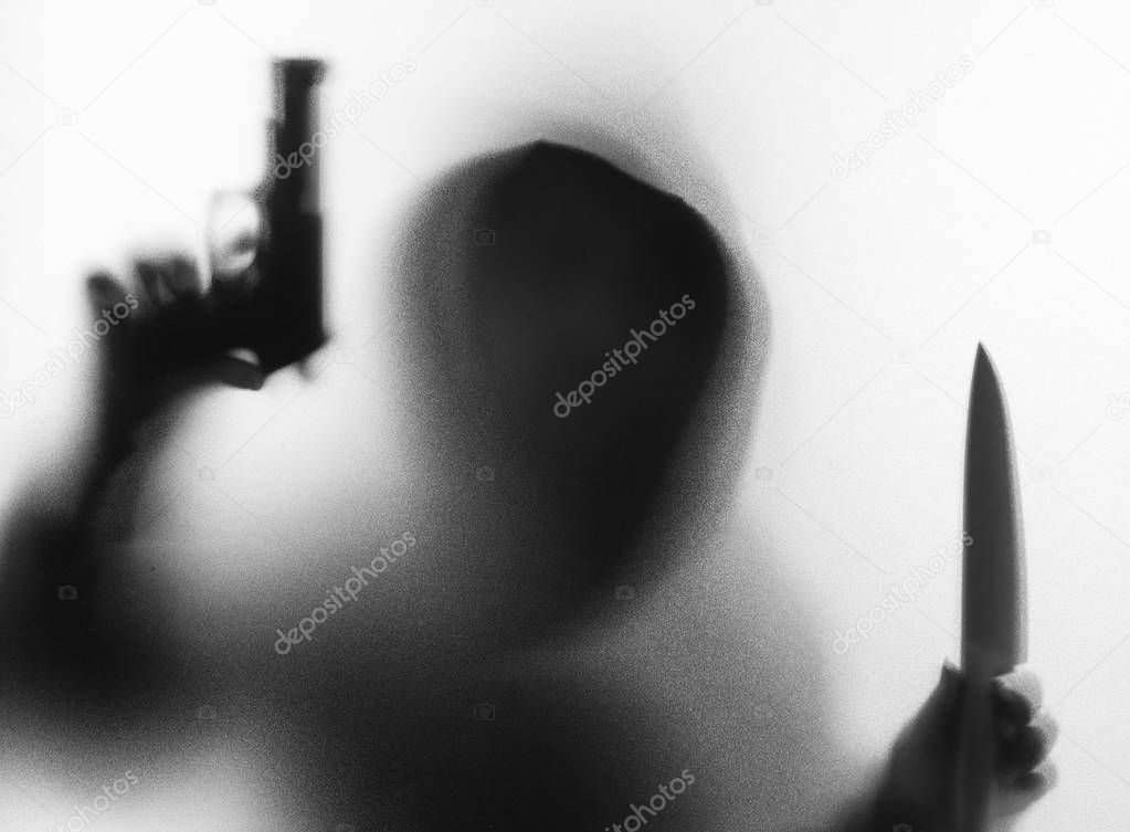 Shadow blur of horror man in jacket with hood knife and gun in h