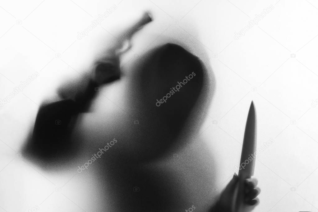 Shadow blur of horror man in jacket with hood knife and gun in h