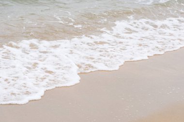 Okyanus dalgaları yorgun sahilde.