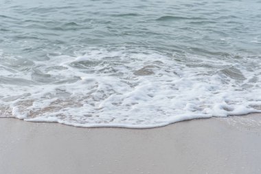 Okyanus dalgaları yorgun sahilde.