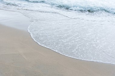 Okyanus dalgaları yorgun sahilde.