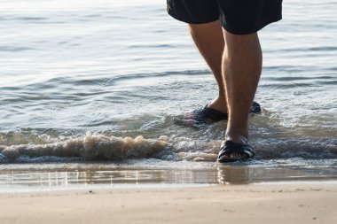Adamın bacakları plaj ve su.