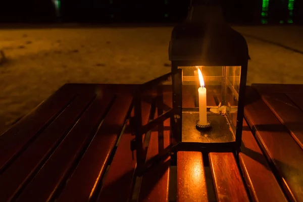 Eine Kerzenlampe auf einem Tisch am Meer in der Nacht. — Stockfoto