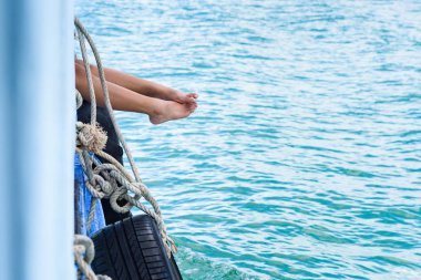 Kenar okyanus kayıkta yolcu kapalı kız bacaklar asmak.