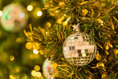 Yeşil yaprakları ağaç ve sezon Noel ve yılbaşı Festivali gibi tebrik içinde bir mağaza aydınlatma sisteminde birçok ayna topları süslemek. Bokeh Noel ışık arka planlar