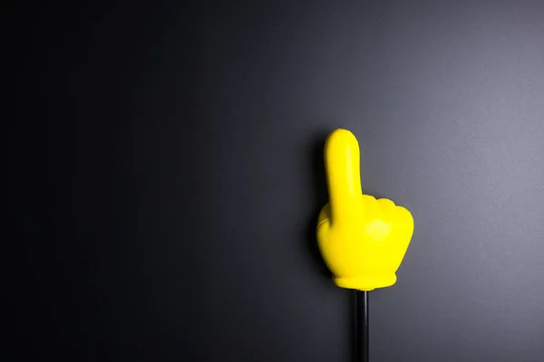 Yellow plastic hand pointing on black background with copy space — Stock Photo, Image