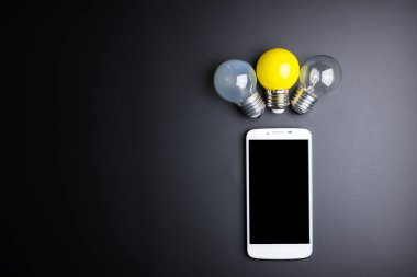 Smartphone ve ampul kopya alanı siyah zemin üzerine.