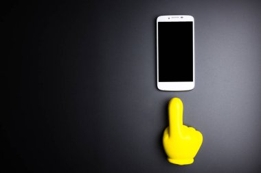 Siyah arka plan üzerinde gösteren bir Smartphone ve sarı plastik el 