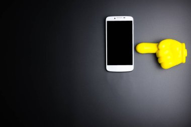 Siyah arka plan üzerinde gösteren bir Smartphone ve sarı plastik el 