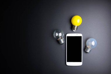 Smartphone ve ampul kopya alanı siyah zemin üzerine.