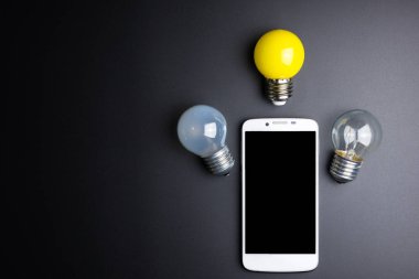 Smartphone ve ampul kopya alanı siyah zemin üzerine.