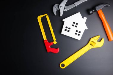 Ahşap beyaz ev ve inşaat araçları oyuncak üzerinde siyah adam