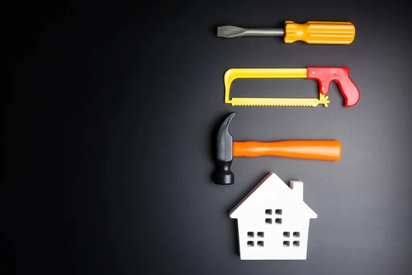 Casa blanca de madera y juguete de herramientas de construcción sobre fondo negro — Foto de Stock