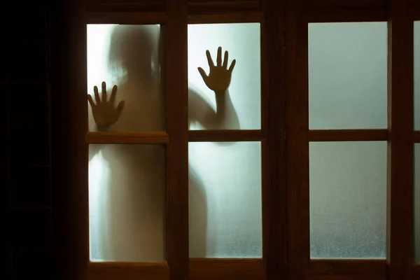 Mujer horrorosa detrás del cristal de la ventana en blanco y negro. Borroso. — Foto de Stock