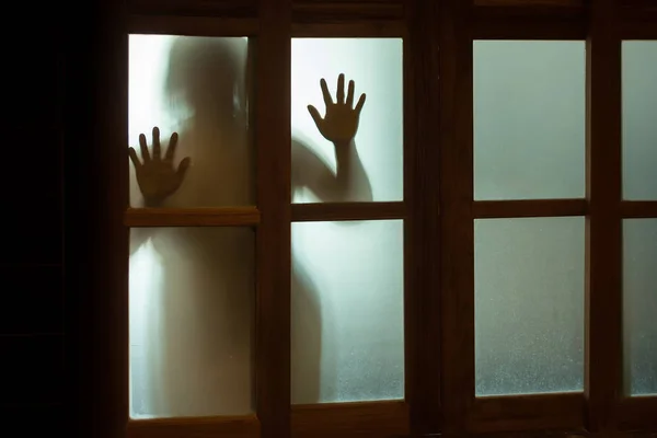 Mujer horrorosa detrás del cristal de la ventana en blanco y negro. Borroso. — Foto de Stock