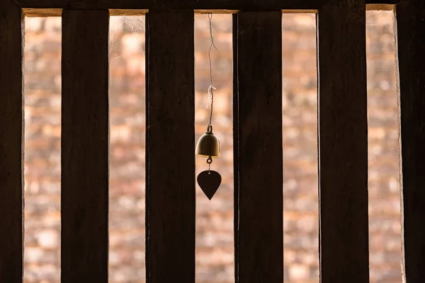 The bell hung at the window with light passing through the woode