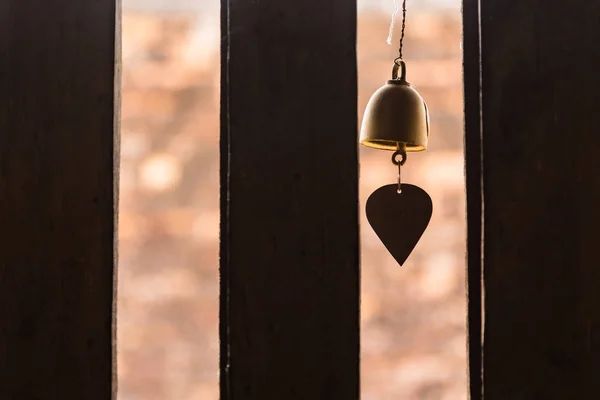 The bell hung at the window with light passing through the woode