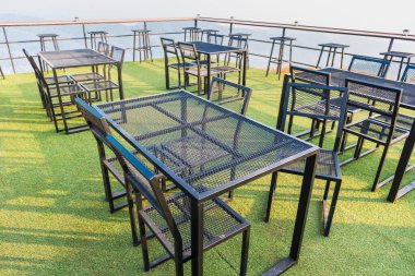 Bir kahve dükkanının çatısında çelik masalar ve sandalyeler..