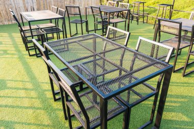 Bir kahve dükkanının çatısında çelik masalar ve sandalyeler..