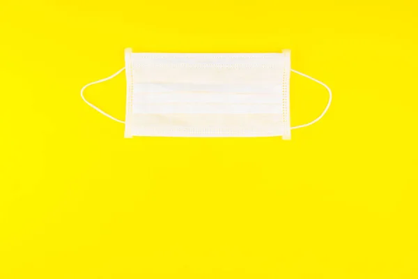 Surgical Face Mask isolated on yellow background. Coronavirus Concept. Medical Face Mask For Stopping The Spread of Virus. Surgical mask with rubber ear straps. surgical mask to cover the mouth nose.