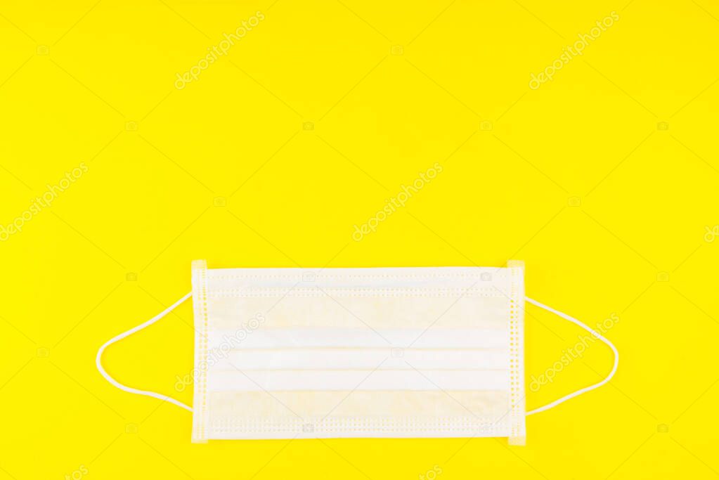 Surgical Face Mask isolated on yellow background. Coronavirus Concept. Medical Face Mask For Stopping The Spread of Virus. Surgical mask with rubber ear straps. surgical mask to cover the mouth nose.