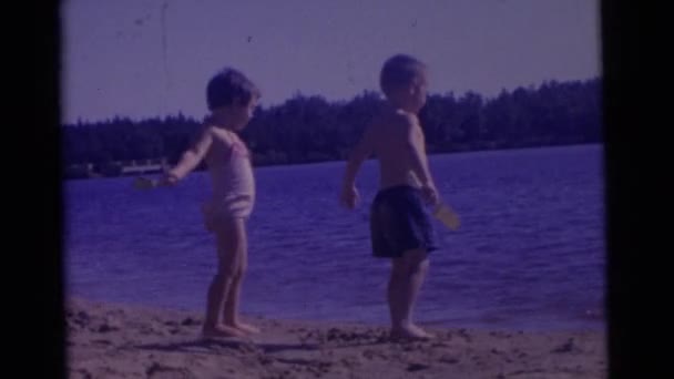 Barn som leker med sand nära floden — Stockvideo