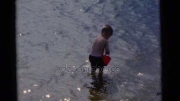 Мальчик собирает речную воду — стоковое видео
