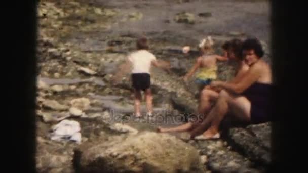 Børn har det sjovt på klippefyldt strand – Stock-video