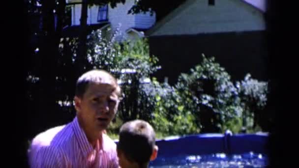Мужчина бросает мальчика в бассейн — стоковое видео
