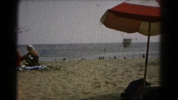Menschen sitzen am Strand — Stockvideo