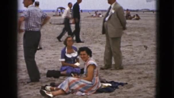Nők és férfiak ül homokos strandon — Stock videók