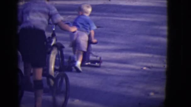 Barn ridning cyklar och trehjulingar ner trottoaren — Stockvideo