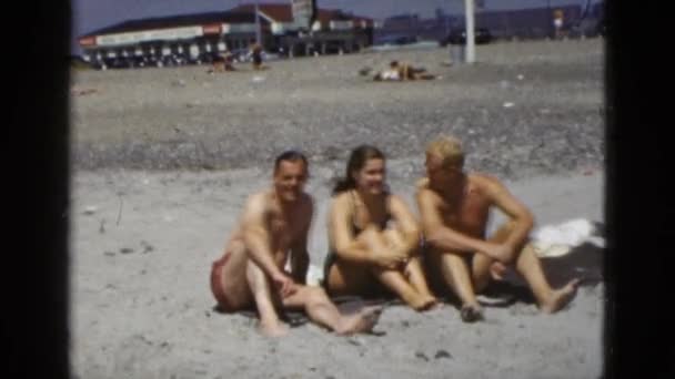 Frau und Männer sitzen am Strand — Stockvideo