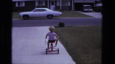 Çocuk üzerinde ön bahçesinde üç tekerlekli bisiklet sürme