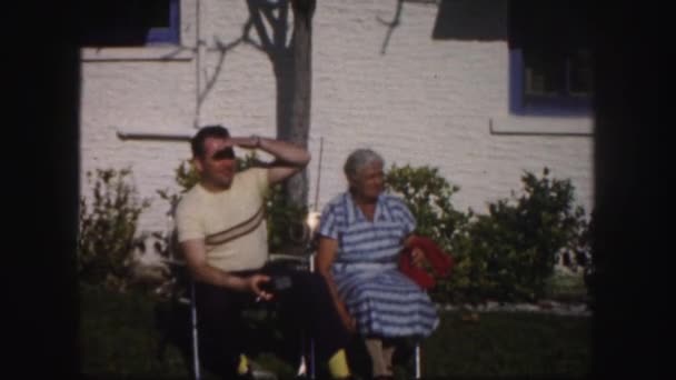 Мужчина и пожилая женщина сидят на заднем дворе — стоковое видео