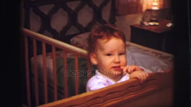 Ребенок стоит на колыбели в своей спальне — стоковое видео