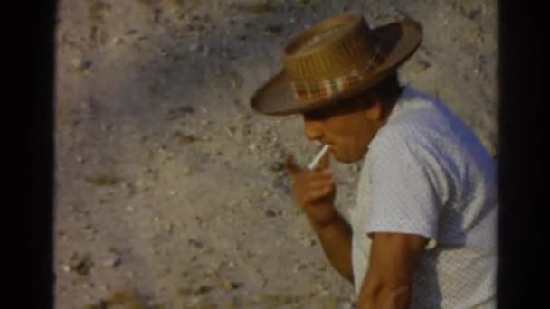 Человек в шляпе курит — стоковое видео