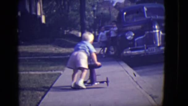Ένα μικρό παιδί με ένα τρίκυκλο να πιέζεται από ένα μεγαλύτερο αγόρι — Αρχείο Βίντεο
