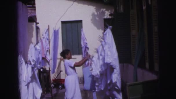 Woman doing laundry outside clothesline hanging sheets — Stock Video
