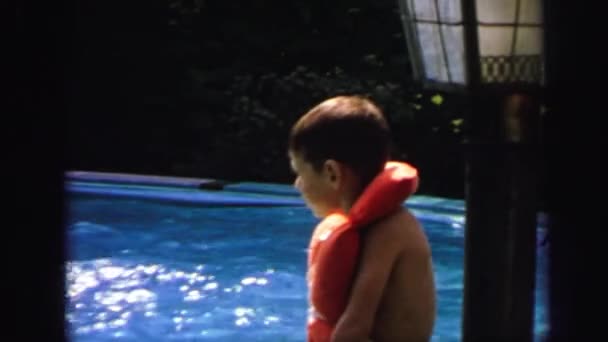 Kid wearing lifejacket and swimming in poolside — Stock Video