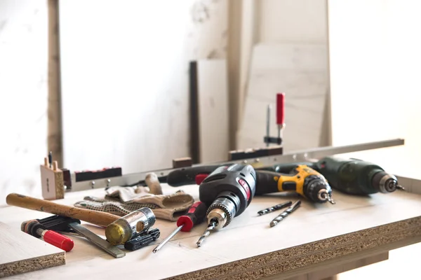 На столе находятся инструменты для сборки мебели: дрель, отвертка, молоток, молоток, зажим, перчатки — стоковое фото